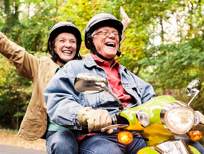 Retired couple riding a scooter.