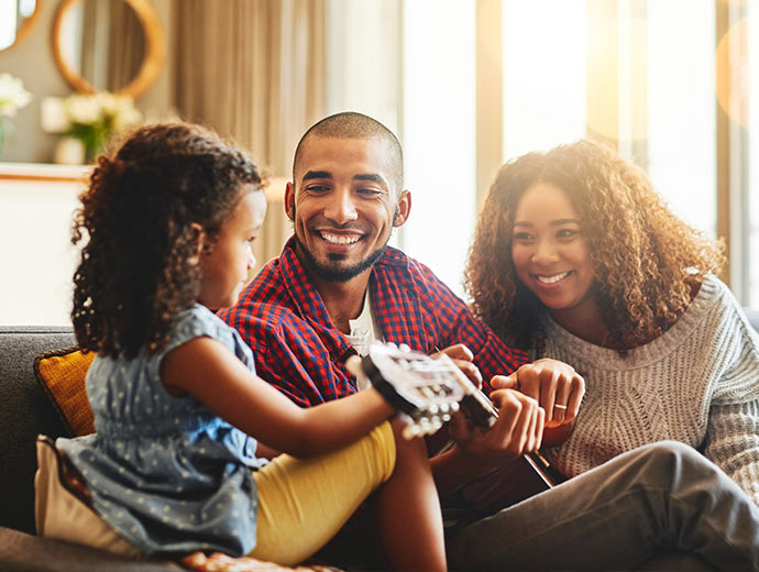 Family smiling and singing on their couch.